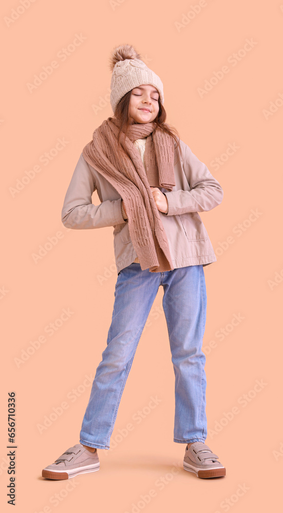 Cute little girl in winter clothes on beige background