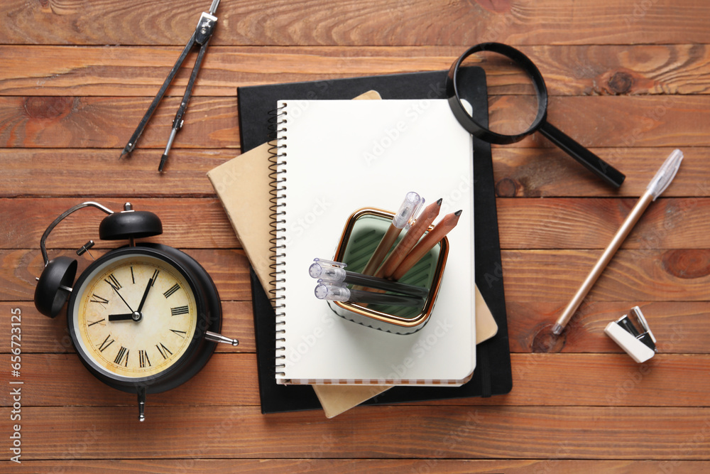 Composition with stationery and alarm clock on wooden background