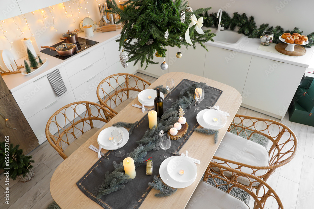 Interior of modern kitchen with festive table setting, glowing lights and Christmas decorations