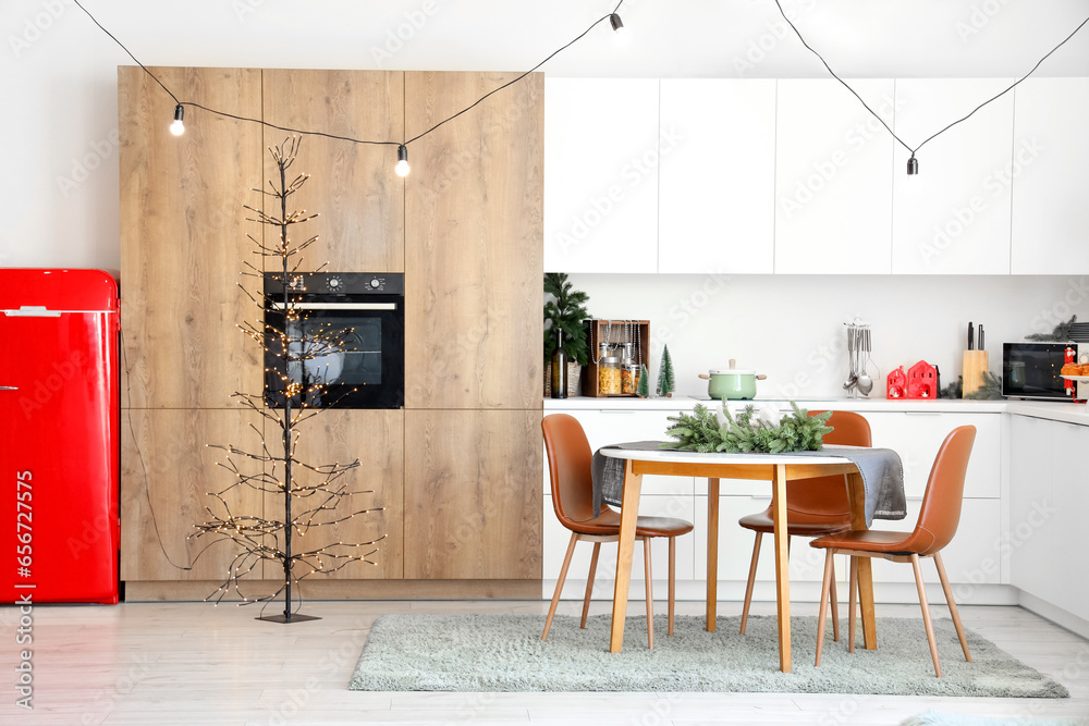 Interior of modern kitchen with festive table setting, Christmas tree and decor