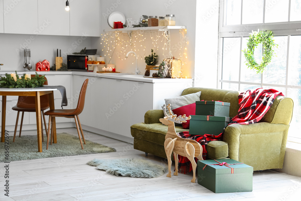 Interior of modern kitchen with green sofa, Christmas decorations and festive table setting