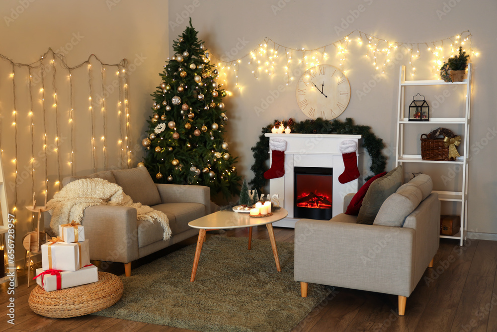 Interior of festive living room with Christmas tree, glowing lights, fireplace and sofas