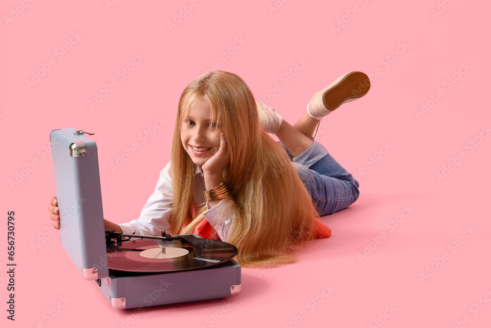 Little girl with record player lying on pink background