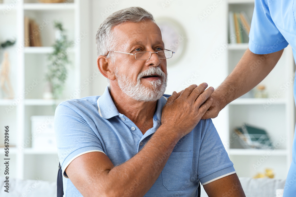 Senior man in wheelchair with nurse at home, closeup