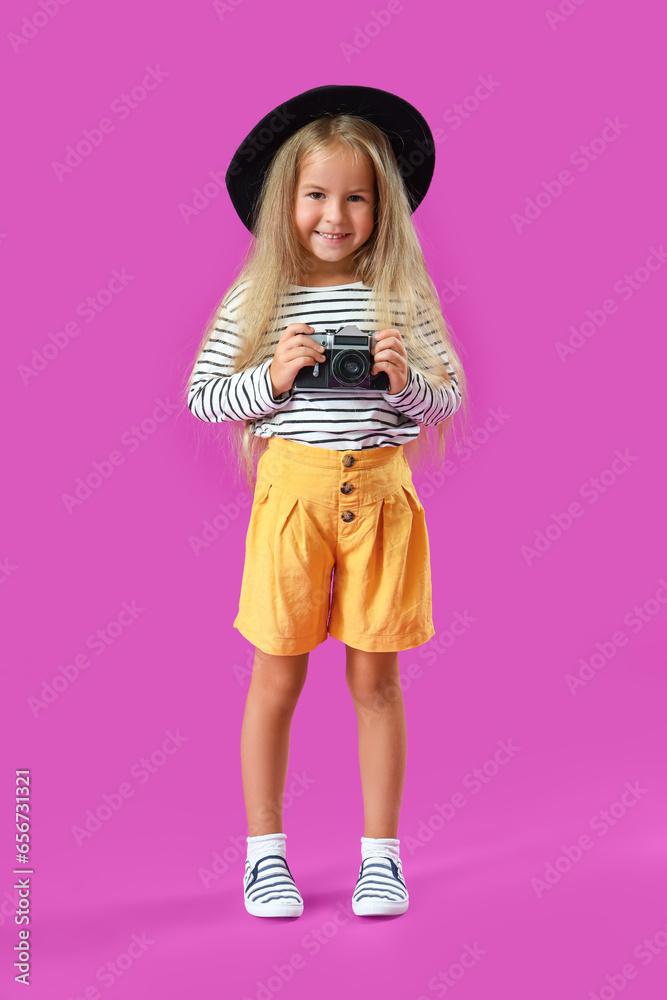 Cute little girl with photo camera on purple background