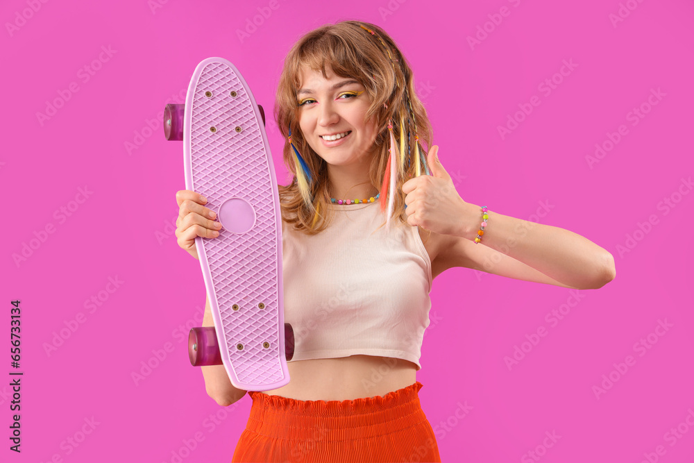 Young woman with skateboard showing thumb-up on purple background