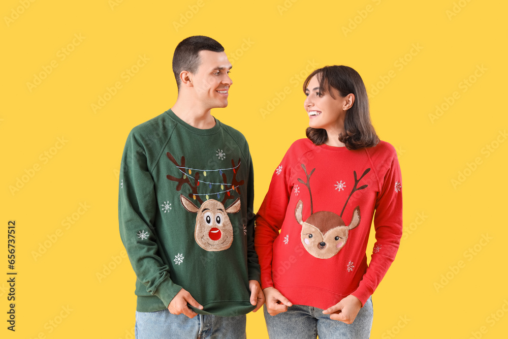 Beautiful young couple in Christmas clothes on yellow background