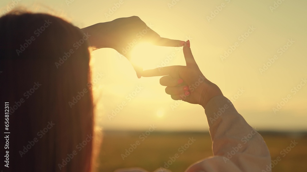 Beautiful girl shows her fingers frame symbol, sun, Sees like in movies. Hands of young female director cameraman making frame gesture at sunset in park. Seeing world as different. Business planning