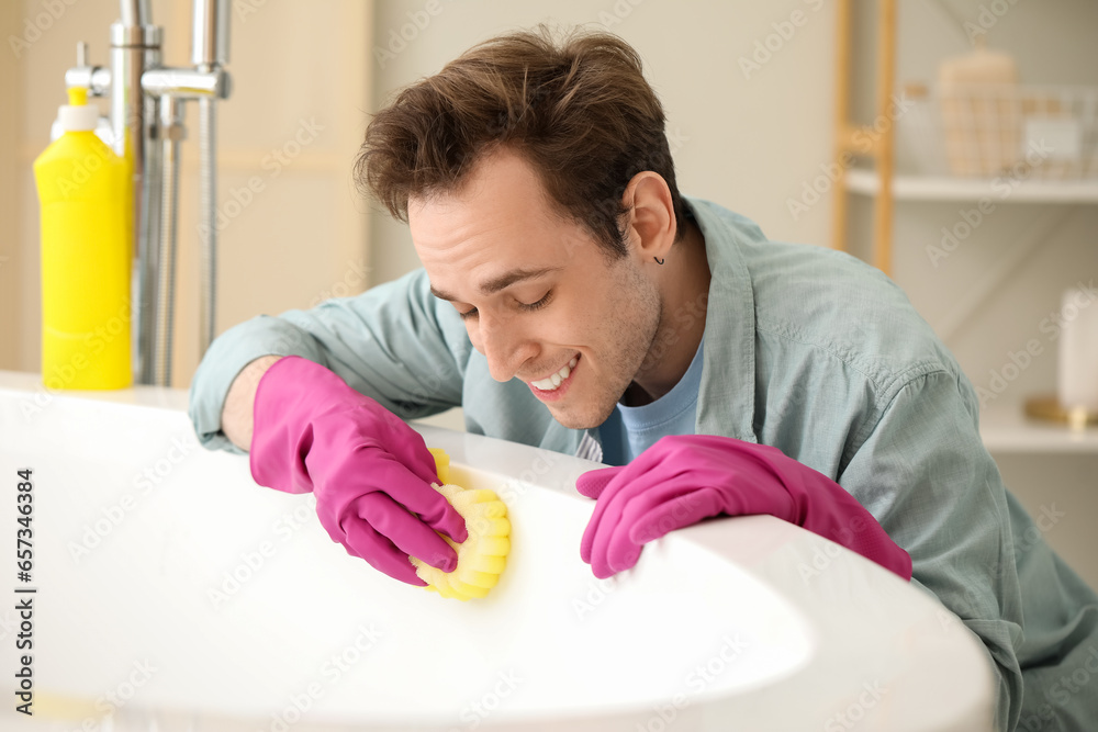 Young man cleaning bathtub at home