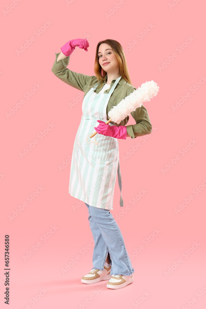 Young woman with pp-duster showing muscles on pink background