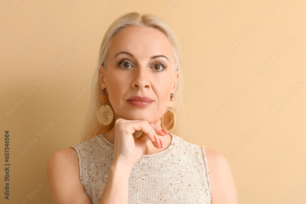 Mature blonde woman on beige background, closeup