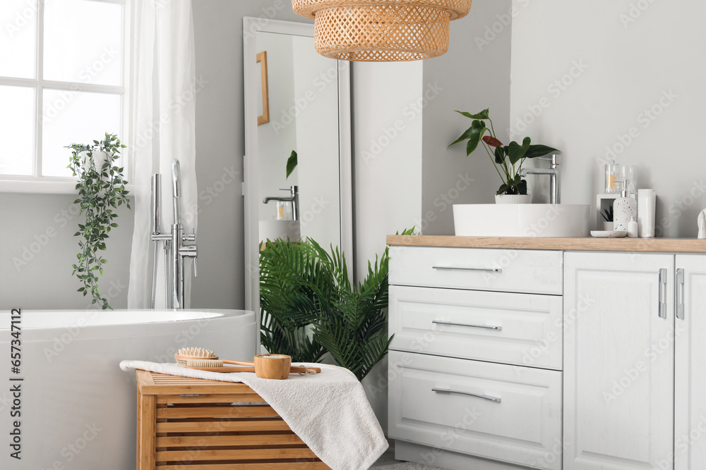 Interior of light bathroom with sink bowl on white counters, mirror and bathtub