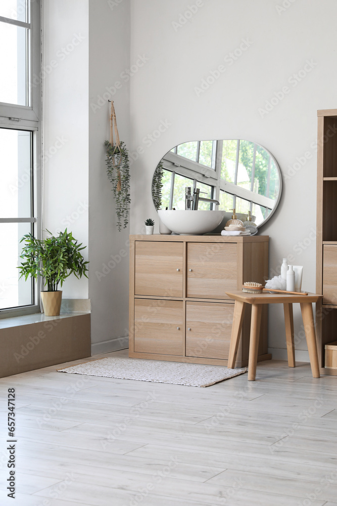 Interior of light bathroom with sink bowl on wooden cabinet and mirror