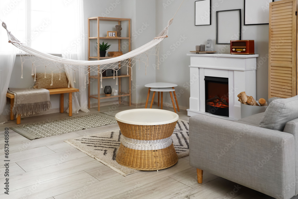 Interior of light living room with fireplace and hammock