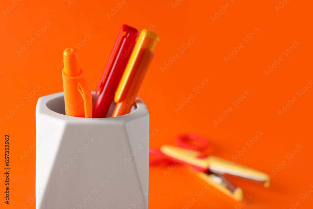 Holder with pens on color background, closeup