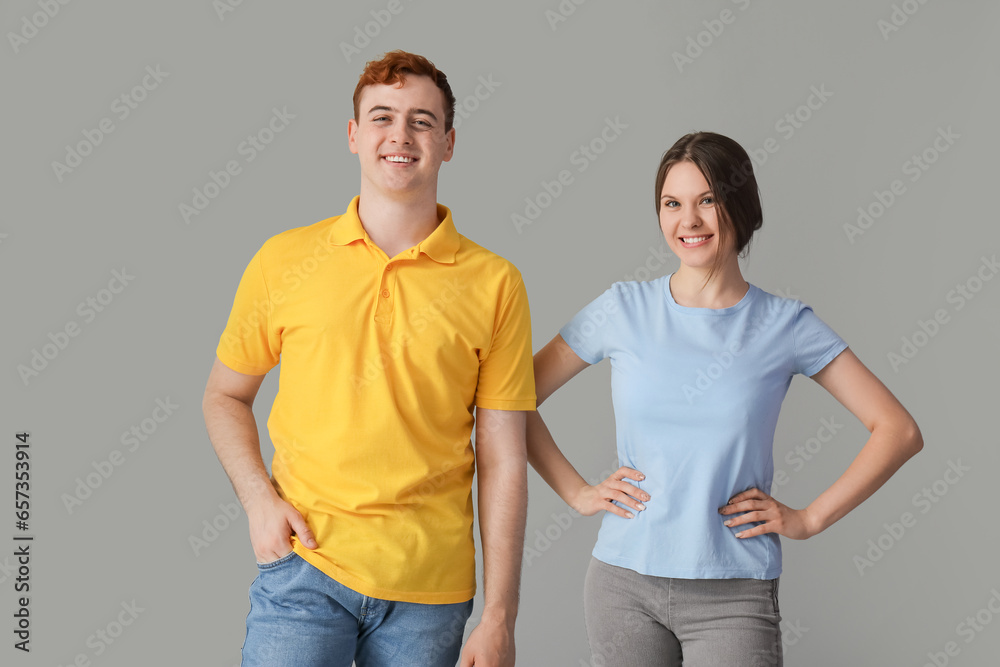 Young couple in t-shirts on grey background