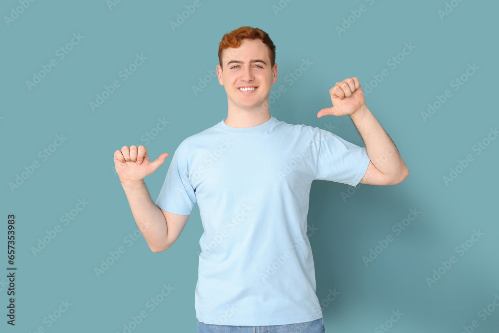 Young man pointing at his t-shirt on blue background