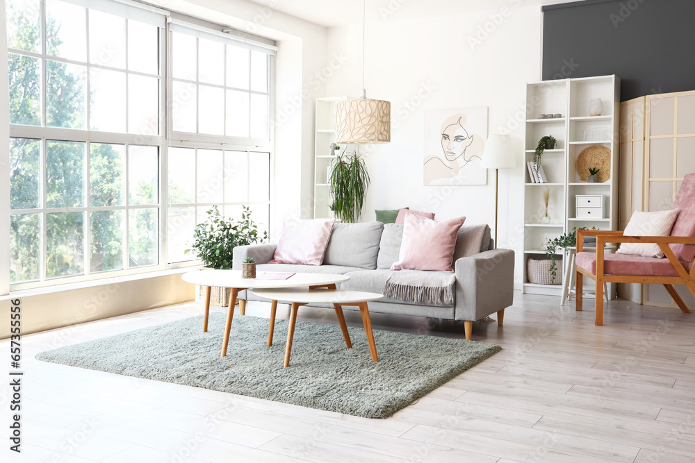 Interior of light living room with grey sofa and stylish coffee table