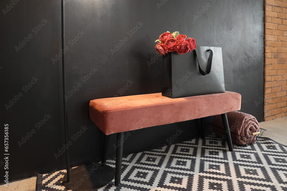 Shopping bag with flowers on pink bench in stylish room