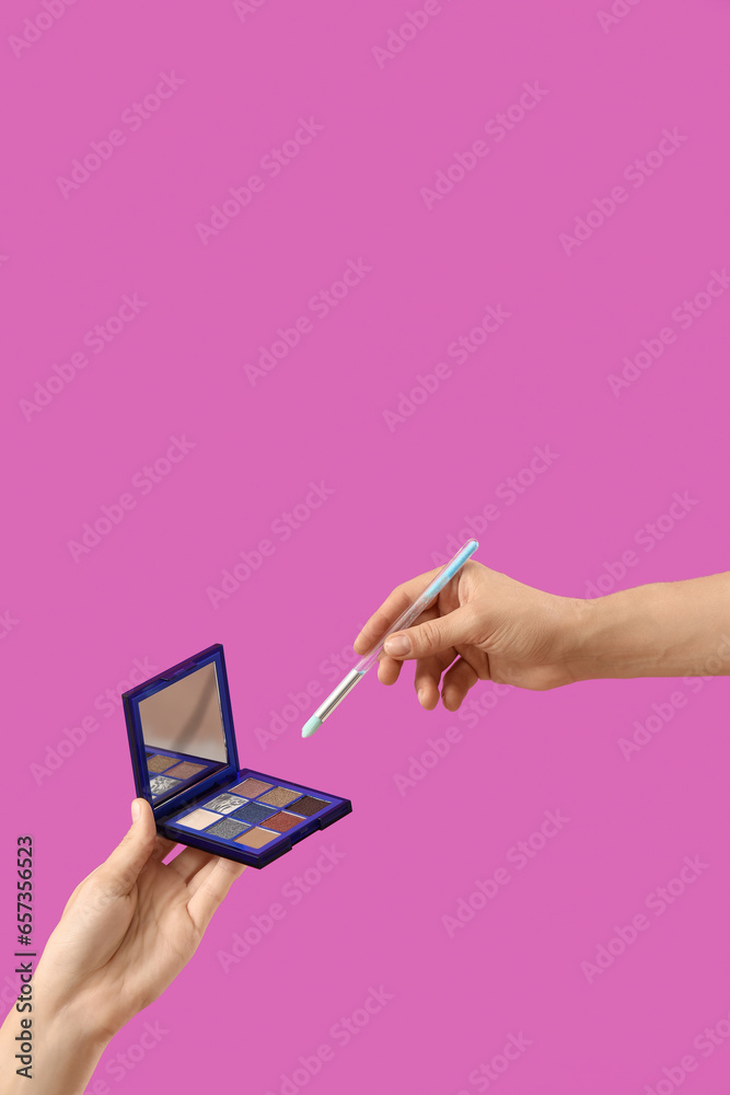 Women with eyeshadows and makeup brush on pink background