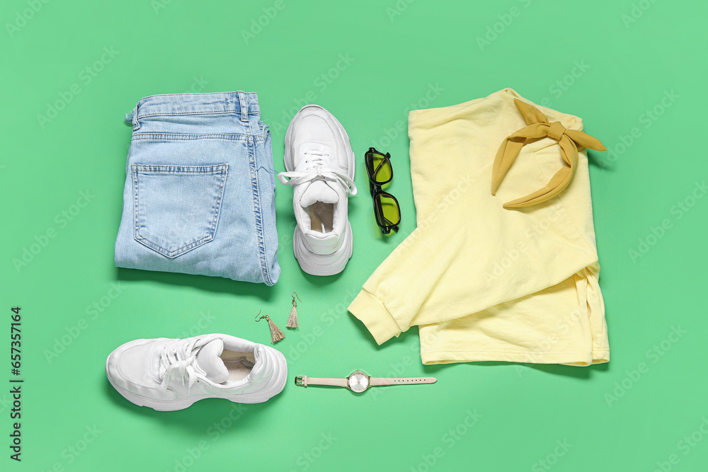 Composition with stylish female clothes, accessories and sneakers on green background