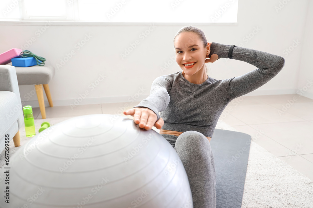 Sporty young woman training with fitball at home