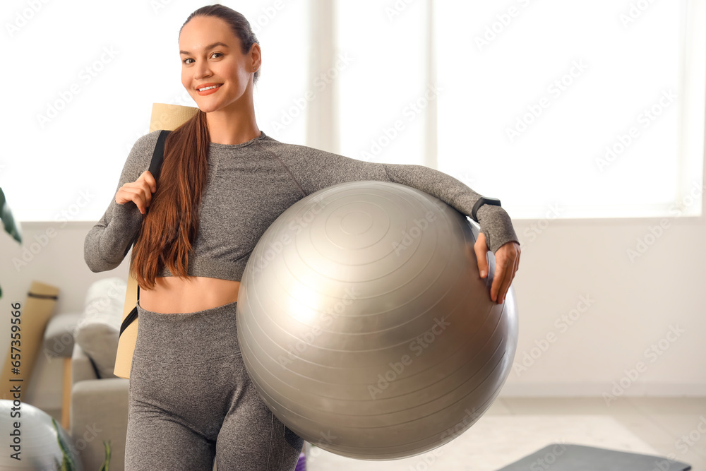 Sporty young woman with fitball at home