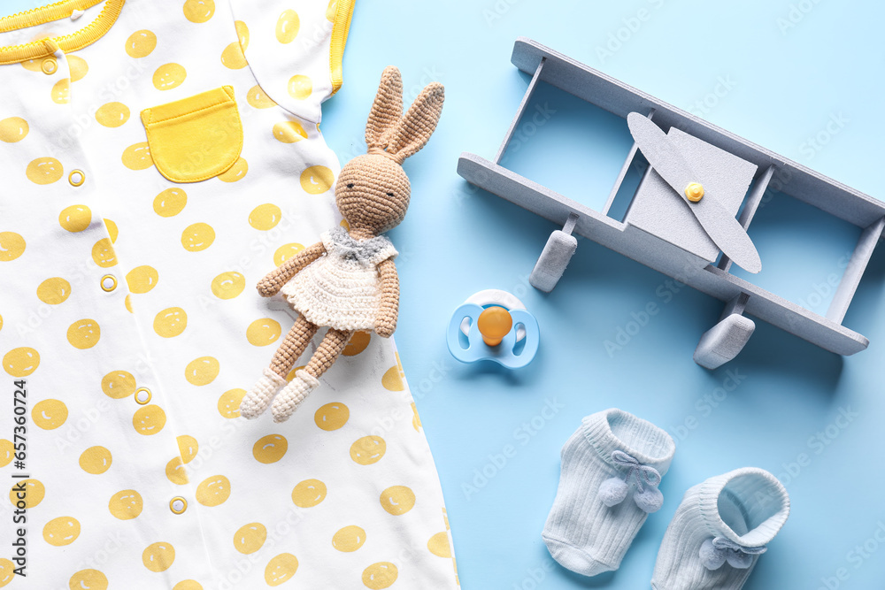 Composition with baby clothes, pacifier and toys on color background