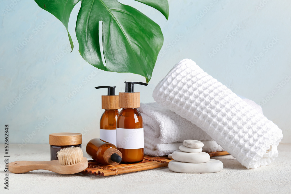 Composition with different cosmetic products, spa accessories and palm leaf on light background