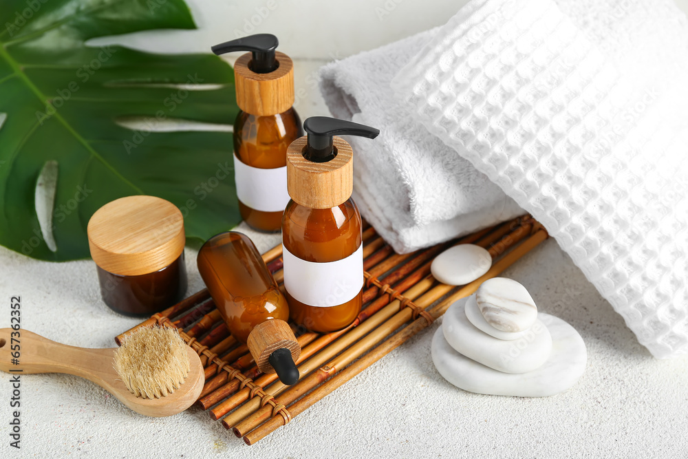 Composition with different cosmetic products, spa accessories and palm leaf on light background