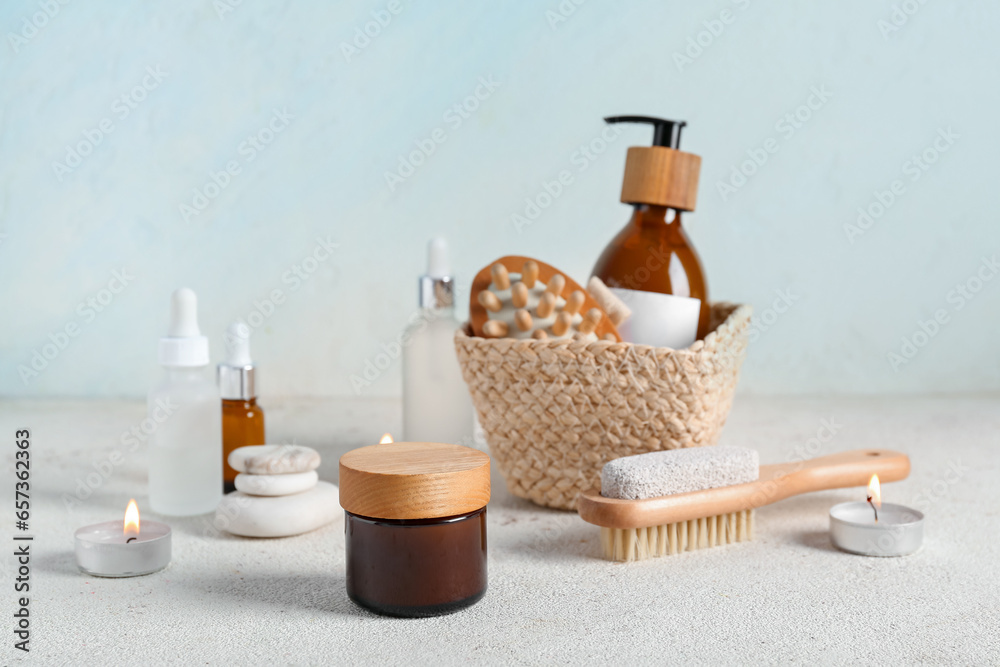 Composition with cosmetic products, spa accessories and burning candles on light background