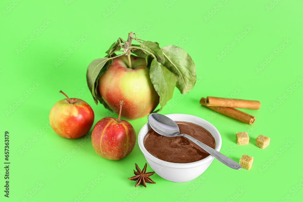 Composition with bowl of tasty apple jam and ingredients on green background