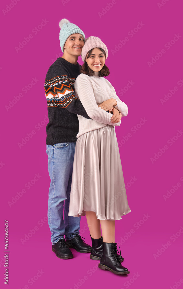 Happy young couple in warm clothes on purple background