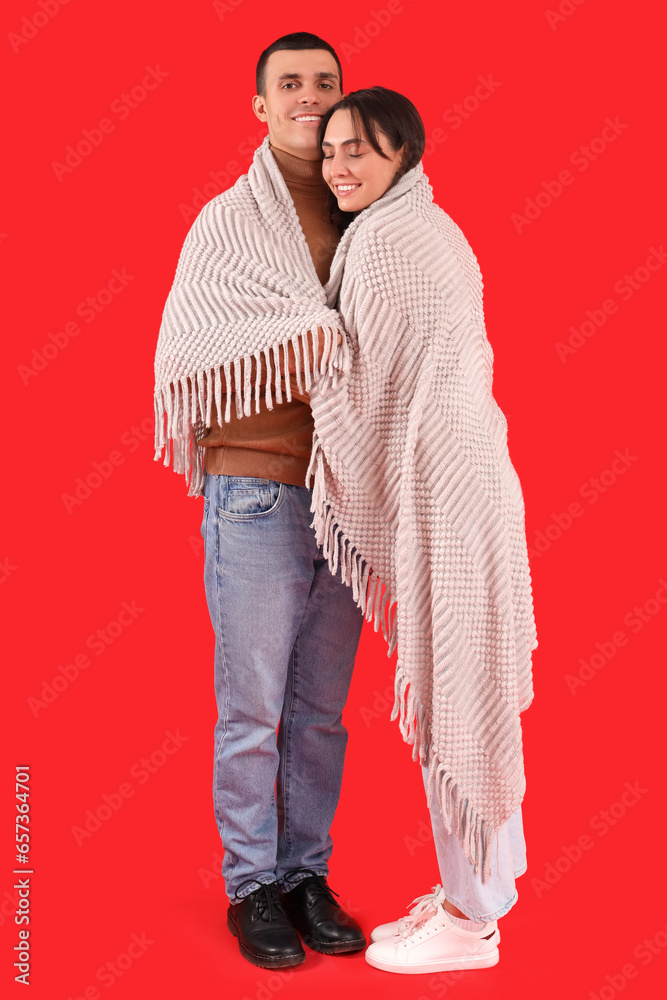 Happy young couple with plaid on red background