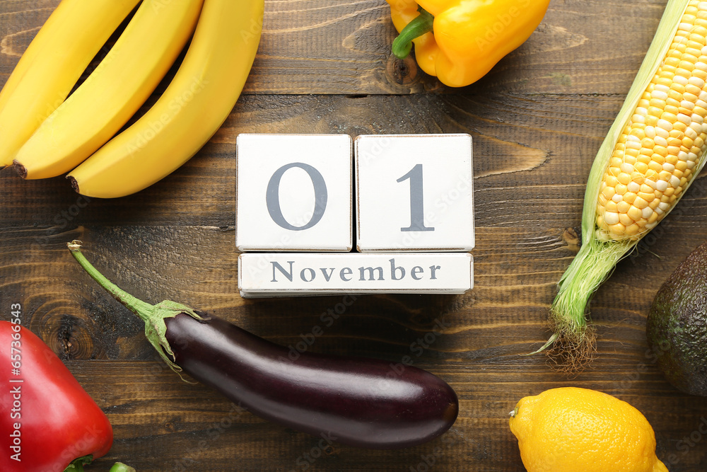 Fresh vegetables, fruits and cube calendar with date NOVEMBER 1 on wooden background. World Vegan Day concept