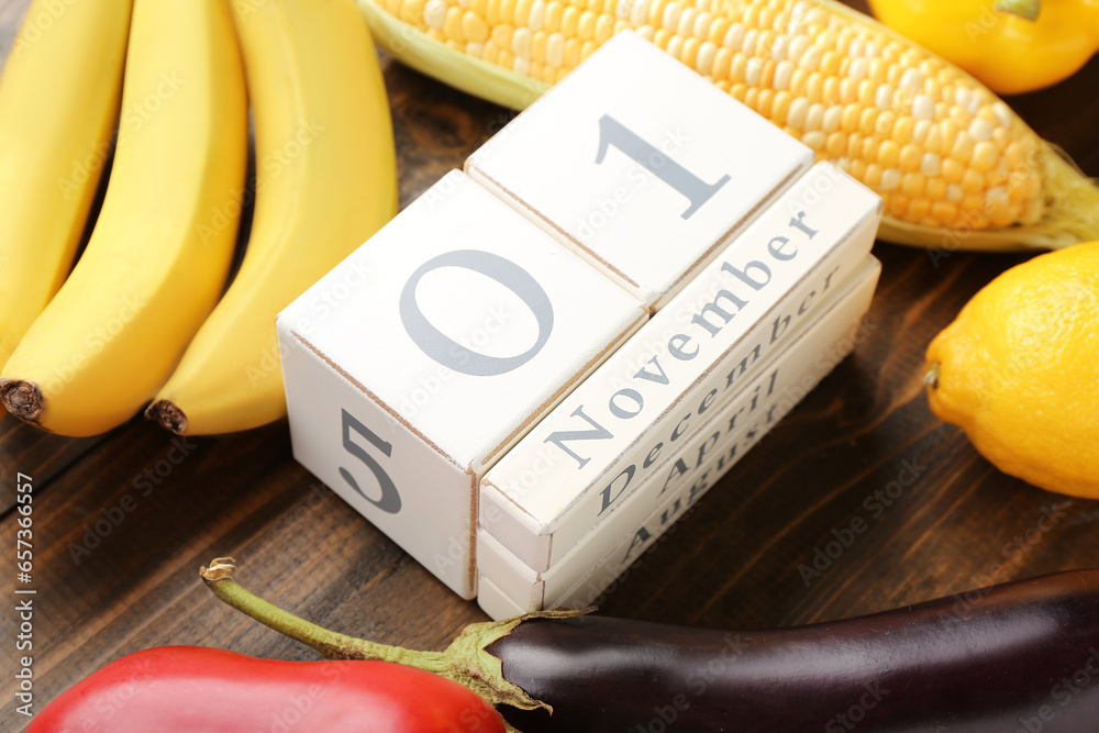 Fresh vegetables, fruits and cube calendar with date NOVEMBER 1 on wooden background. World Vegan Day concept