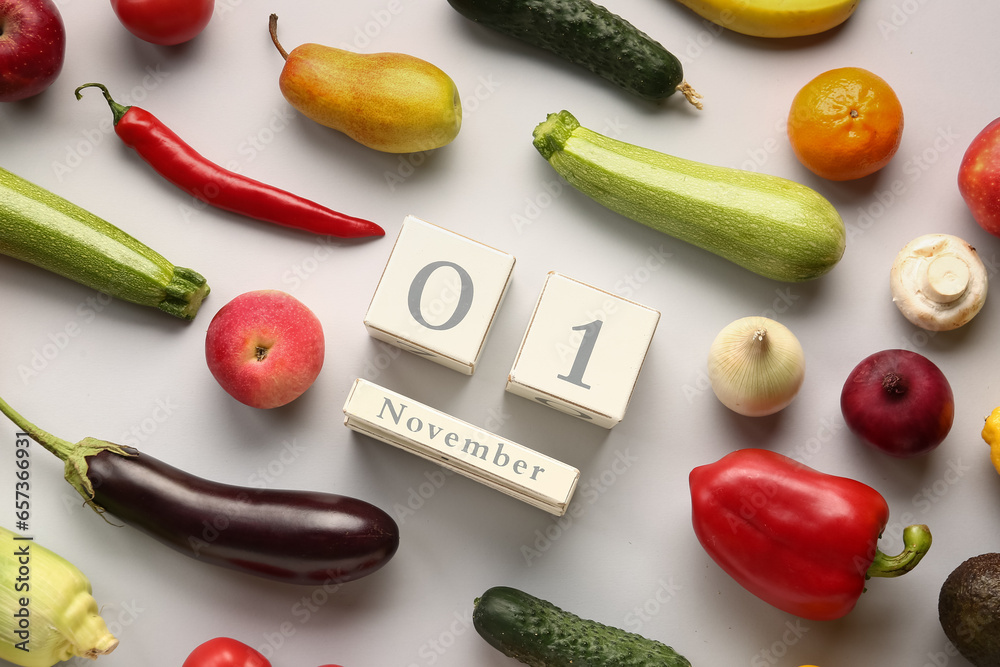 Fresh vegetables, fruits and cube calendar with date NOVEMBER 1 on grey background. World Vegan Day concept