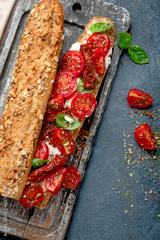 Fresh baguette with Caprese. Delicious sandwich with with tomatoes and mozzarella cheese with fresh basil leaves. Italian food conception.