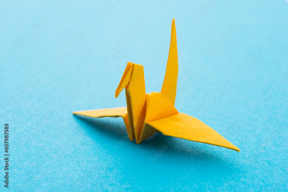 Yellow origami paper crane on blue background