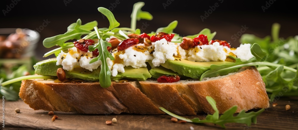 Healthy toast with goat cheese avocado arugula and sun dried tomatoes on wooden table close up