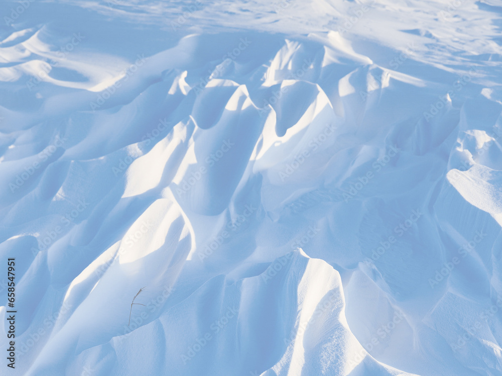 Snow texture. Wind sculpted patterns on snow surface. Wind in the tundra and in the mountains on the surface of the snow sculpts patterns and ridges (sastrugi). Arctic, Polar region. Winter background