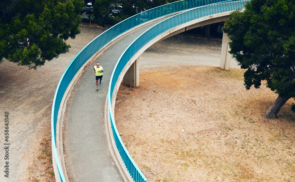 Above, man and running on bridge in nature, countryside or outdoor in environment with path in woods. Athlete, run or walking on road for cardio, fitness or exercise in forest with eco infrastructure