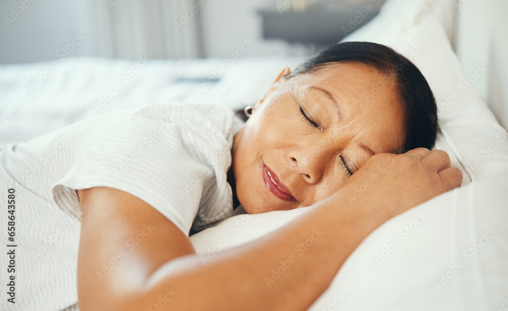 Mature, woman and calm while sleeping in bed with good dream, head on pillow and peace. Asian, elderly person and face in bedroom, alone and smile with happiness while rest with retirement in home