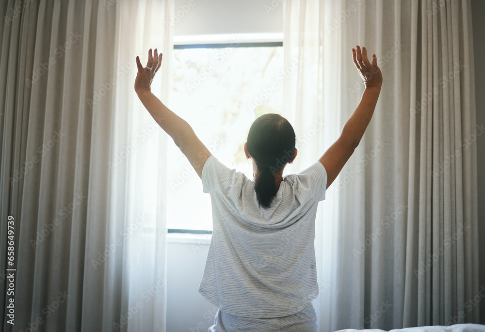 Stretching, curtains and back of woman at window for wake up, sunrise or good morning routine in bedroom at home. Awake, arms or get up from comfortable sleep to start bright new sunny day after rest