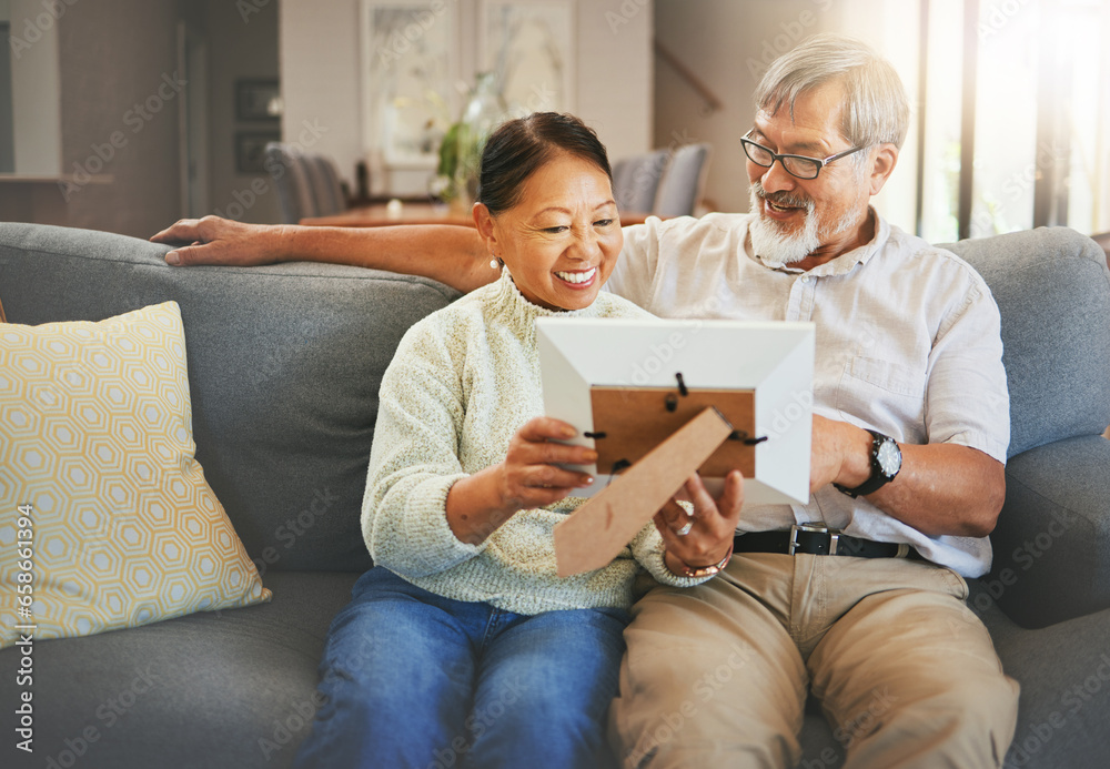 Elderly couple, happy and together with memory or photograph on sofa with smile in living room. Senior man, woman and married with embrace by sit, bond and love in relationship for vacation, holiday