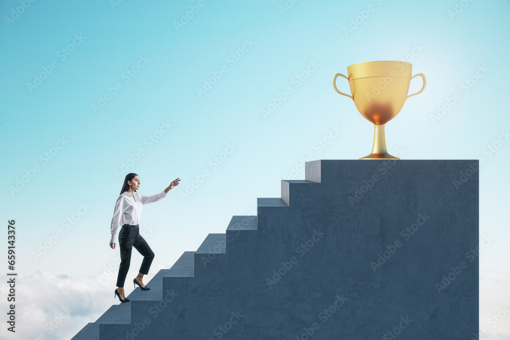 Side view of young european businesswoman climbing stairs to golden winners cup on bright blue sky background. Success and career growth concept.