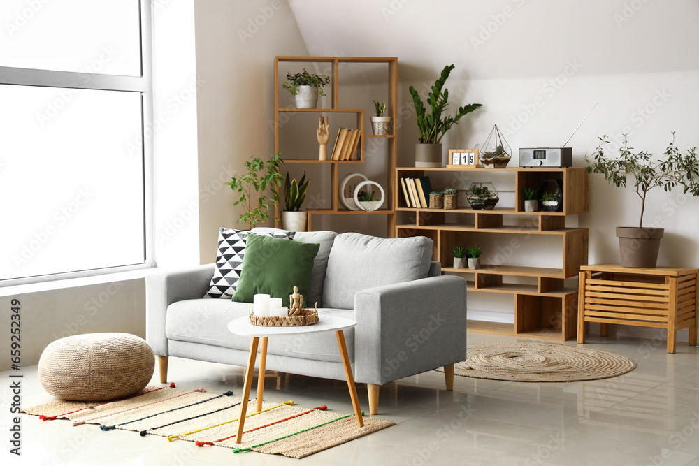 Interior of light living room with sofa, florariums and bookcase