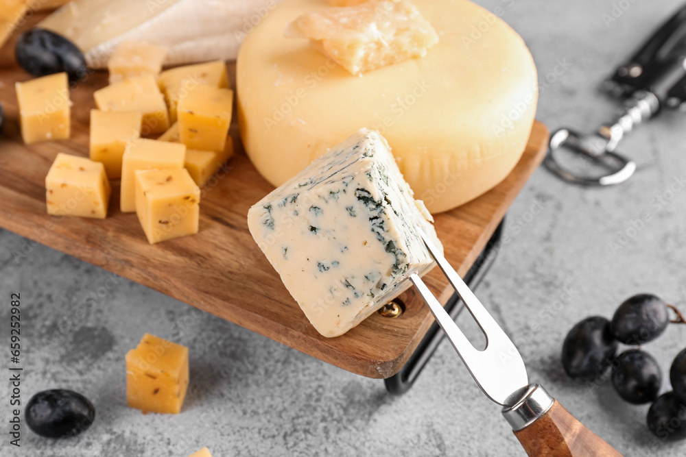 Fork with piece of tasty cheese on light background