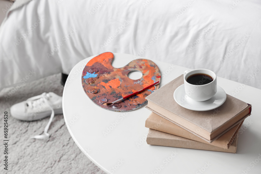 Palette, books and cup of coffee on table in childrens bedroom