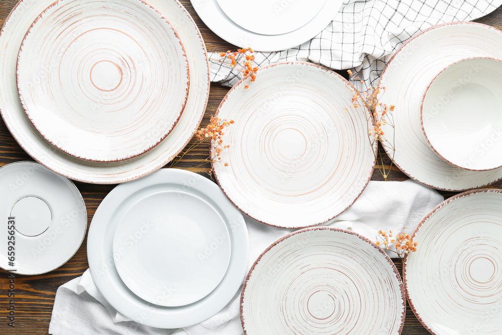 Clean ceramic plates, cup and floral decor on wooden table